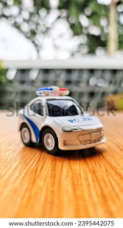 Close up bokeh photo of a boy's toy police car. White, has a siren.auto, automobile, automotive, background, blue, car, childhood, children, children playing, children toy, city, closeup, drive, fast,