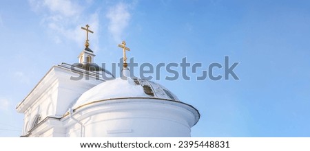 Church of the Resurrection of the Lord in Verh-Nevinsky, Russia. White snow covered domes with gold crosses on blue sky background. Banner with copy space.
