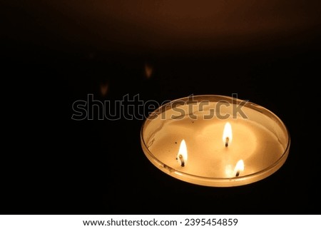 a candle with three wicks that burns in the dark