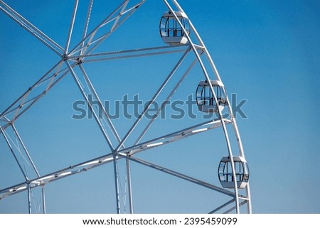 Big, tall white Ferris wheel in front of a perfect blue sky Royalty-Free Stock Photo #2395459099