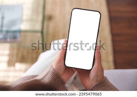 Top view mockup image of a woman holding mobile phone with blank desktop white screen Royalty-Free Stock Photo #2395479065