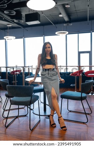 Young female concentrates on photosession at coworking zone. Brunette female employee with bare legs in contemporary lounge zone Royalty-Free Stock Photo #2395491905