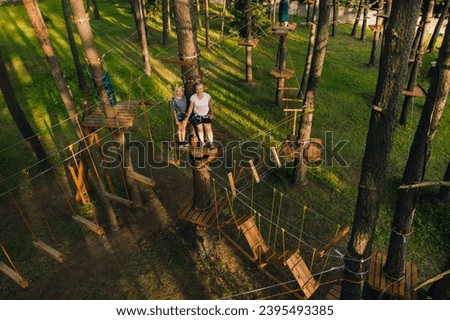 A girl passes an obstacle in a rope town. A girl in a forest rope park.