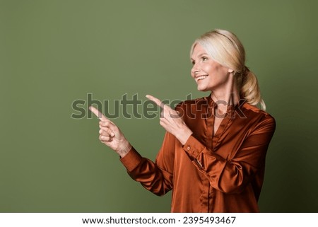 Photo portrait of lovely senior lady point empty space cheerful wear trendy satin brown garment isolated on khaki color background