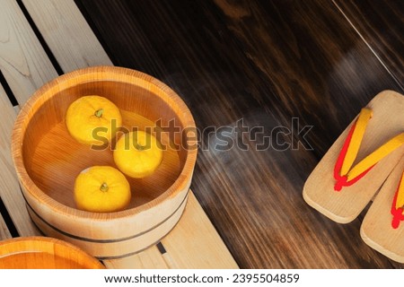 hot spa image: yuzu fruits for yuzu bath in wooden bath bucket and wooden Japanese sandals(geta) Royalty-Free Stock Photo #2395504859
