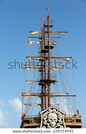 Masts and sails of huge sailing boat against the background of blue sky  