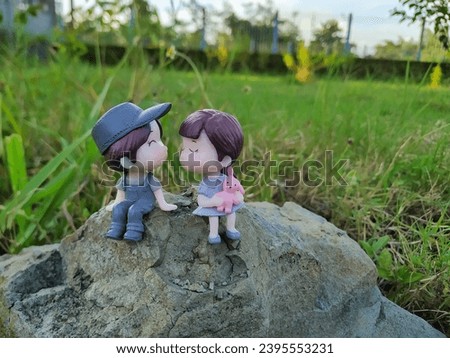 Romantic mini figures sitting together on a large rock with a bokeh background