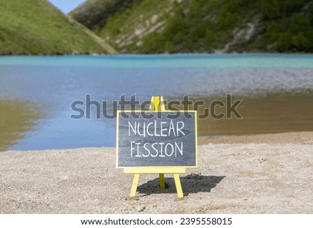 Nuclear fission symbol. Concept words Nuclear fission on beautiful black chalk blackboard. Chalkboard. Beautiful mountain lake background. Business science nuclear fission concept. Copy space. Royalty-Free Stock Photo #2395558015