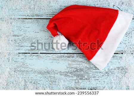 Santa red hat with snowflakes on color wooden background