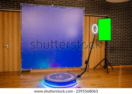 Defocused view of a 360 photo booth used at an event. Banner and TV green screen. Royalty-Free Stock Photo #2395568063