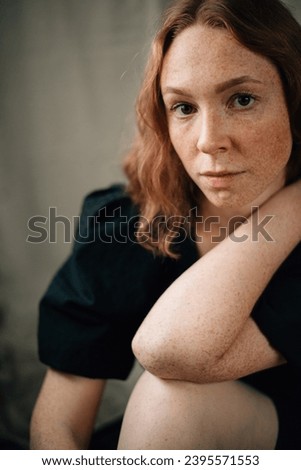 portrait of a red-haired curly girl in a black dress. High quality photo