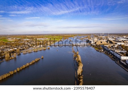 River IJssel being twice its size during high water levels in winter rains seen from above passing countenance boulevard of Zutphen, The Netherlands. Aerial of flooded floodplains at city limits. Royalty-Free Stock Photo #2395578407