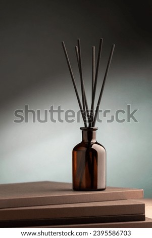 Aroma reed diffuser dark glass on green background with volumatic light Royalty-Free Stock Photo #2395586703
