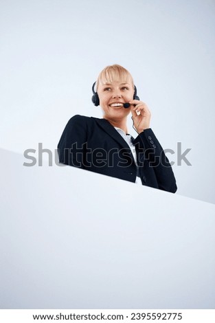 Mockup, smile and a call center woman in studio on a white background for help, crm or telemarketing. Space, customer support and headset with a happy young employee with poster for sales service Royalty-Free Stock Photo #2395592775
