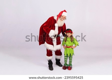 Real Santa Claus with a little girl dressed as an elf on a white background with free space for text. Christmas