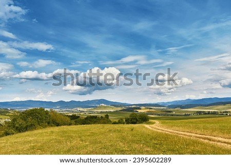 Slovakia summer landscape. Green summer fields, meadows, hills of Tatra mountains. Travel in vacations. Rural Road in Spis region, Slovakia. Spissky hrad national park on background