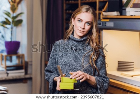 Portrait of smiling female interior designer sitting at office desk color comparison equipment