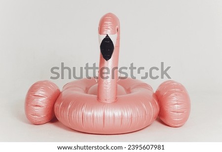 Summer fun concept with pink inflatable flamingo head on a white background with copy space