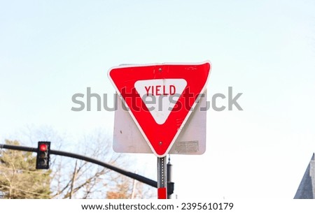 yield sign on road, symbolizing caution and giving way to oncoming traffic, against a clear blue sky