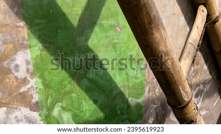 The display of an abstract photo of a bamboo ladder and a concrete wall background with green paint strokes.