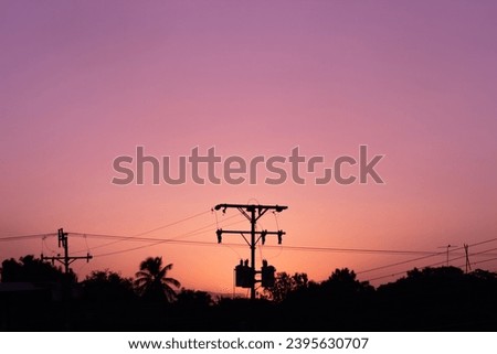 Silhouette of high voltage electric pole at sunset sky background.