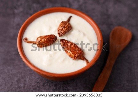 Bowl of homemade sour cream curd yogurt Dahi fresh herbs curry leaf Kerala India. Dairy product obtained coagulating milk process curdling. probiotic food tasty curd rice curry spices Royalty-Free Stock Photo #2395656035