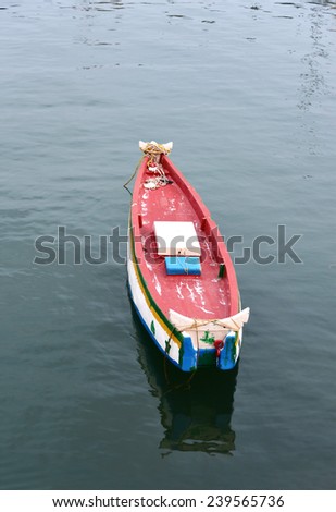 Top view of a small colorful isolated fishing boat in the lake. Ripples and reflection in the stagnant waters. 