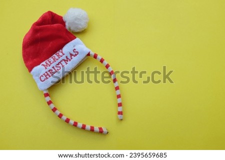Beautiful headband 
 Decorative red Santa Hat isolate on a yellow backdrop.
concept of joyful Christmas party,New year is coming soon, festive season decoration with Christmas elements