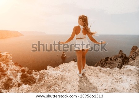 Woman travel sea. Young Happy woman posing on a beach over the sea on background of volcanic rocks, like in Iceland, sharing travel adventure journey