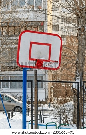 Basketball shield on a snow-covered court on a winter day