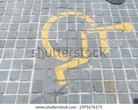 Wheelchair logo with yellow paint color on the black pavement floor
