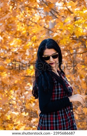 A striking image of a Persian woman posing in the midst of yellow autumn leaves. The woman's modern dress contrasts with the natural beauty of the surroundings, creating a sense of harmony and balance