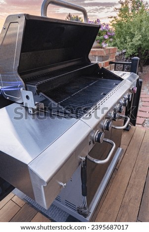 Morning on a summer day. Six burner gas grill on a fully furnished back patio of a single home.