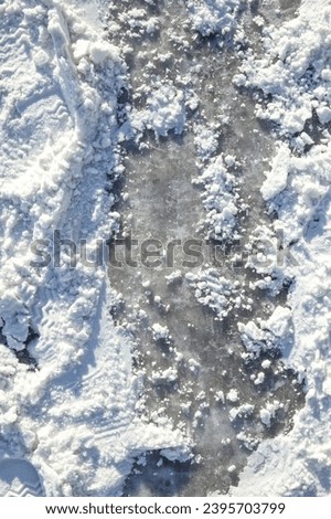 Snow covered street with ice layer. Top view of road after snowstorm and cold night. Slippery dangerous driving conditions. Stay at home, don't travel advice. Vancouver, BC, Canada. Selective focus.  Royalty-Free Stock Photo #2395703799