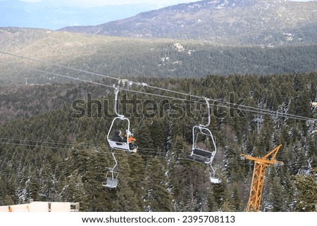 Ski Lift snowy mountain winter forest with chair lift At The Ski Resort in winter. Snowy weather Ski holidays Winter sport and outdoor activities Outdoor tourism, Bursa (Turkey), Uludağ ski lift Royalty-Free Stock Photo #2395708113
