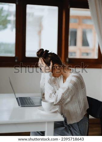Creative young woman working at a desk at home in a cozy interior with a cup of drink, home office freelancer with a smile, communication and education online