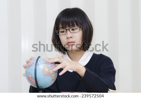 Teenage schoolgirl pointing a place on a globe with her finger