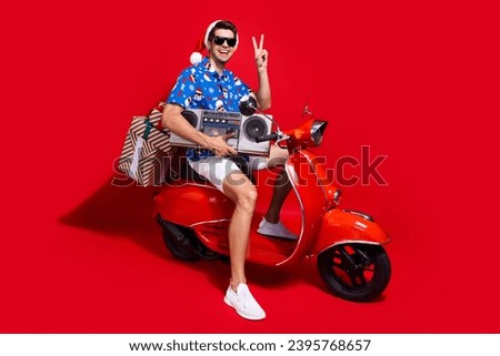 Full body photo of handsome young guy scooter boom box gifts v-sign dressed santa claus print x-mas outfit isolated on red color background