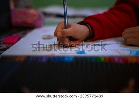 Little girl draws at home, creativity development. POV child painting a picture with school supplies, preschool child painting, child doing homework.