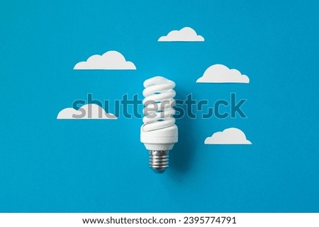Light bulb with white cut out clouds on blue background. Idea concept. Energy and electricity. alternative energy sources. Innovation and thinking out the box symbols. Creativity and inspiration
