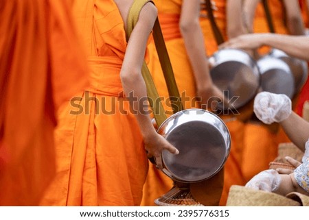 Buddhist alms giving ceremony in the early morning.Monks walk to collect alms and offerings.Sticky rice morning alms giving is held every day in Luang Prabang.Traditional ritual of alms giving in Laos Royalty-Free Stock Photo #2395776315