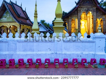 Buddhist alms giving ceremony in the early morning.Monks walk to collect alms and offerings.Sticky rice morning alms giving is held every day in Luang Prabang.Traditional ritual of alms giving in Laos Royalty-Free Stock Photo #2395777777