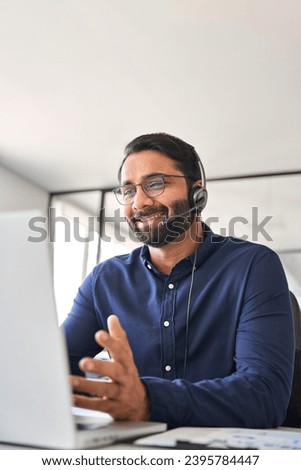 Smiling Indian call center agent wearing headset talking to client working in customer support office. Professional contract service telemarketing operator using laptop having conversation. Vertical Royalty-Free Stock Photo #2395784447