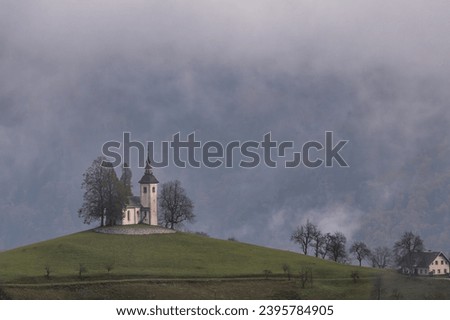 Sv.Tomaz church above Skofja Loka in the autumn foggy day
