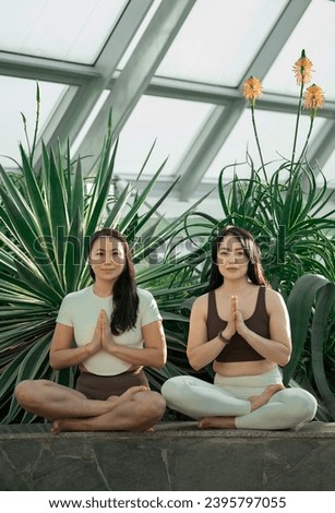 Young Asian women sit in lotus position and hold hands in Namaste pose. High quality photo
