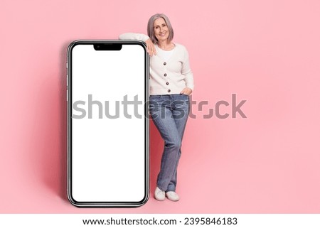 Full length photo of lovely retired lady lean on big smartphone display dressed stylish white garment isolated on pink color background