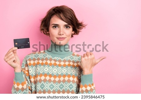 Photo of lovely positive girl hold debit plastic card direct thumb finger empty space isolated on pink color background