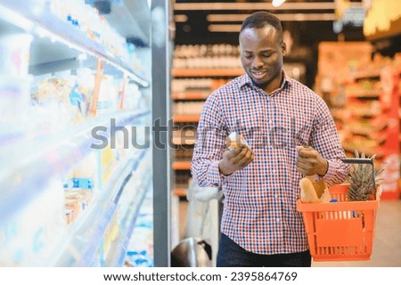 African man shopping at supermarket. Handsome guy holding shopping basket.