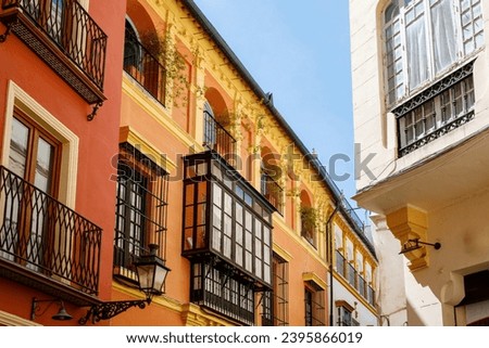 Decorative balconies and windows with gates of old city center house in Seville, Spain