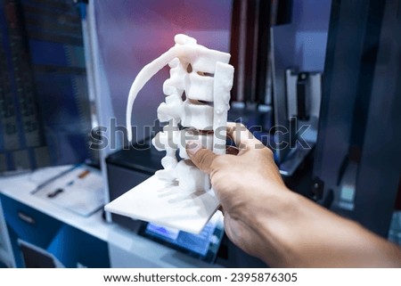hand with 3d printed human spine in 3d printer. Royalty-Free Stock Photo #2395876305